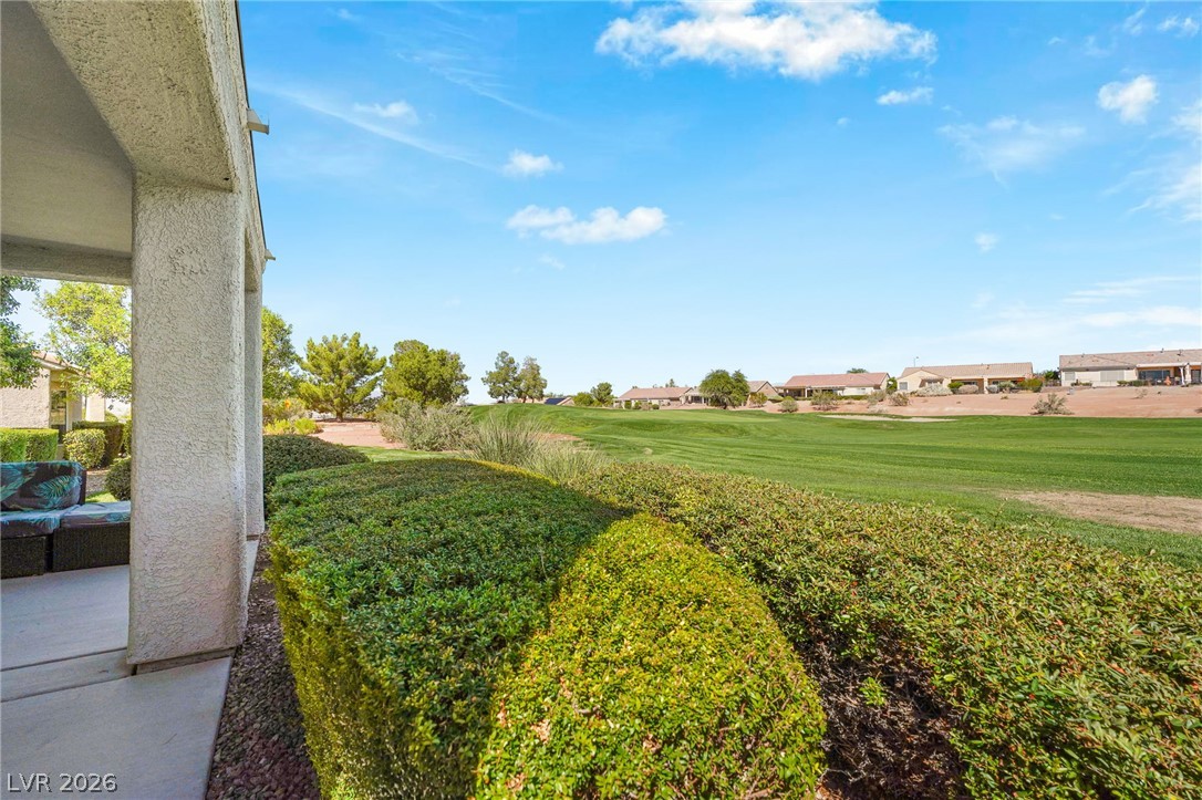 2738 Grand Forks Road Henderson, NV 89052 - Photo 33 of 52 Manicured hedges frame a covered patio opening directly onto a lush green fairway under sunny skies.