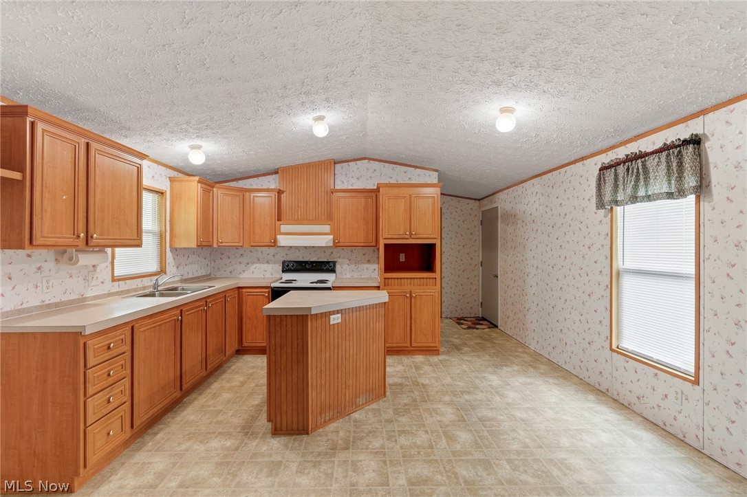 8472 Azalea Road Southwest Dennison, OH 44621 - Photo 19 of 35 Kitchen featuring wood-finish cabinetry, a central island, light-toned countertops, tile-patterned flooring, and a window with blinds