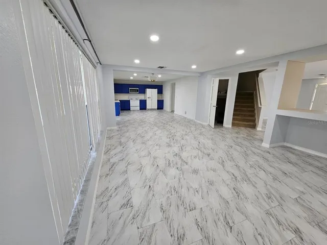 a view of a hallway with wooden floor and kitchen view
