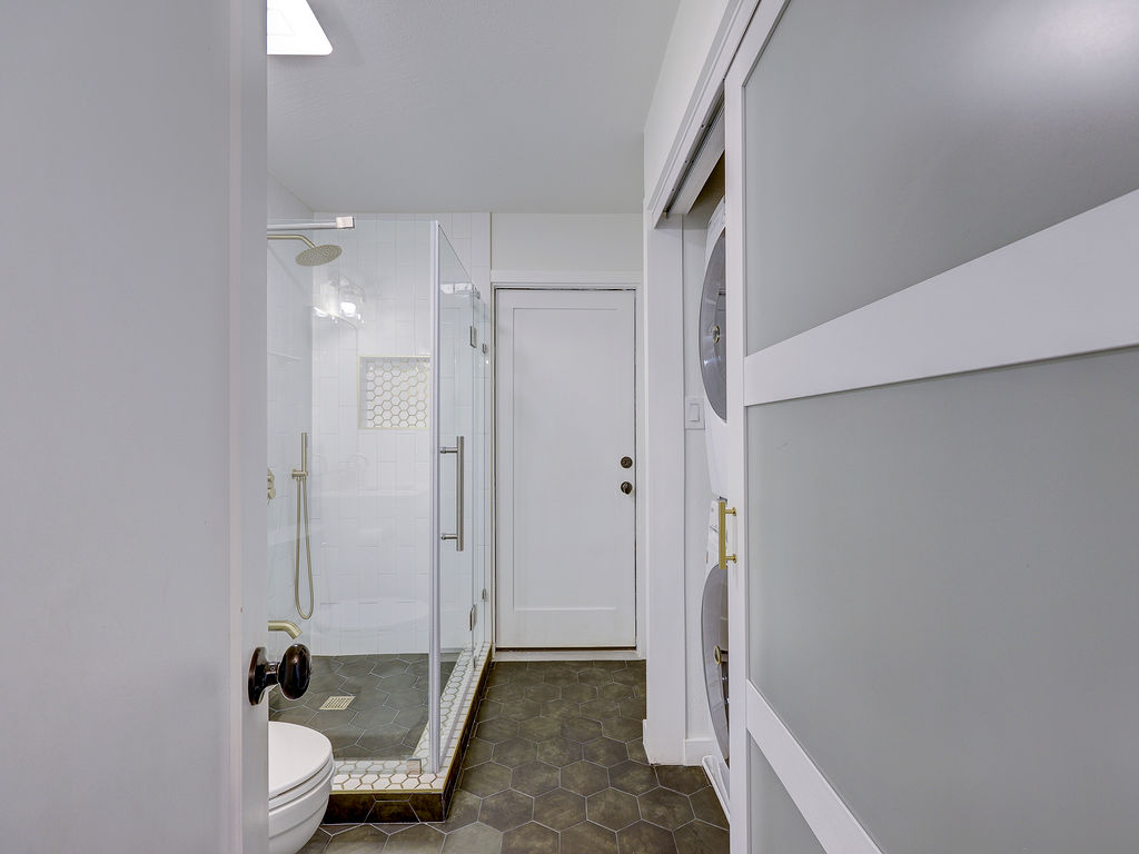 5842 Secrest Drive Austin, TX 78759 - Photo 38 of 40 A well-appointed bathroom features a glass-enclosed shower and a cleverly concealed laundry area.