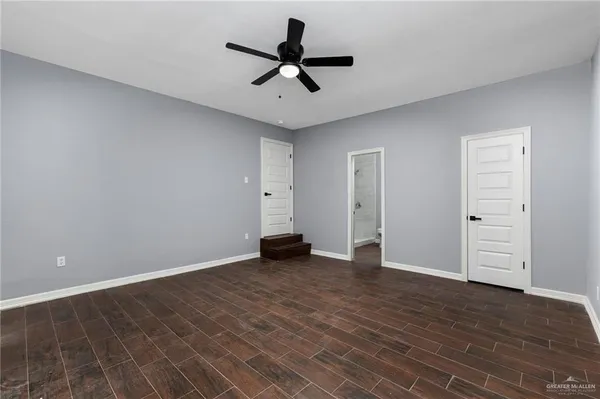 an empty room with wooden floor ceiling fan and windows