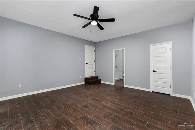 an empty room with wooden floor ceiling fan and windows