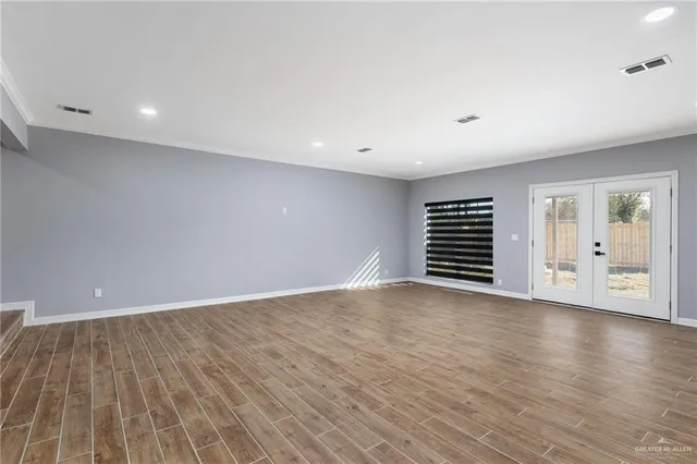a view of an empty room with wooden floor and windows