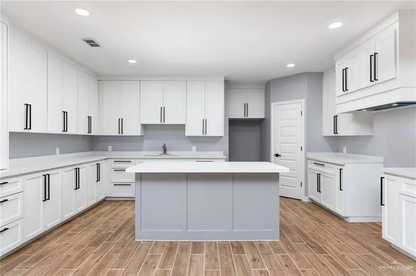 a kitchen with white cabinets appliances a sink and a counter space