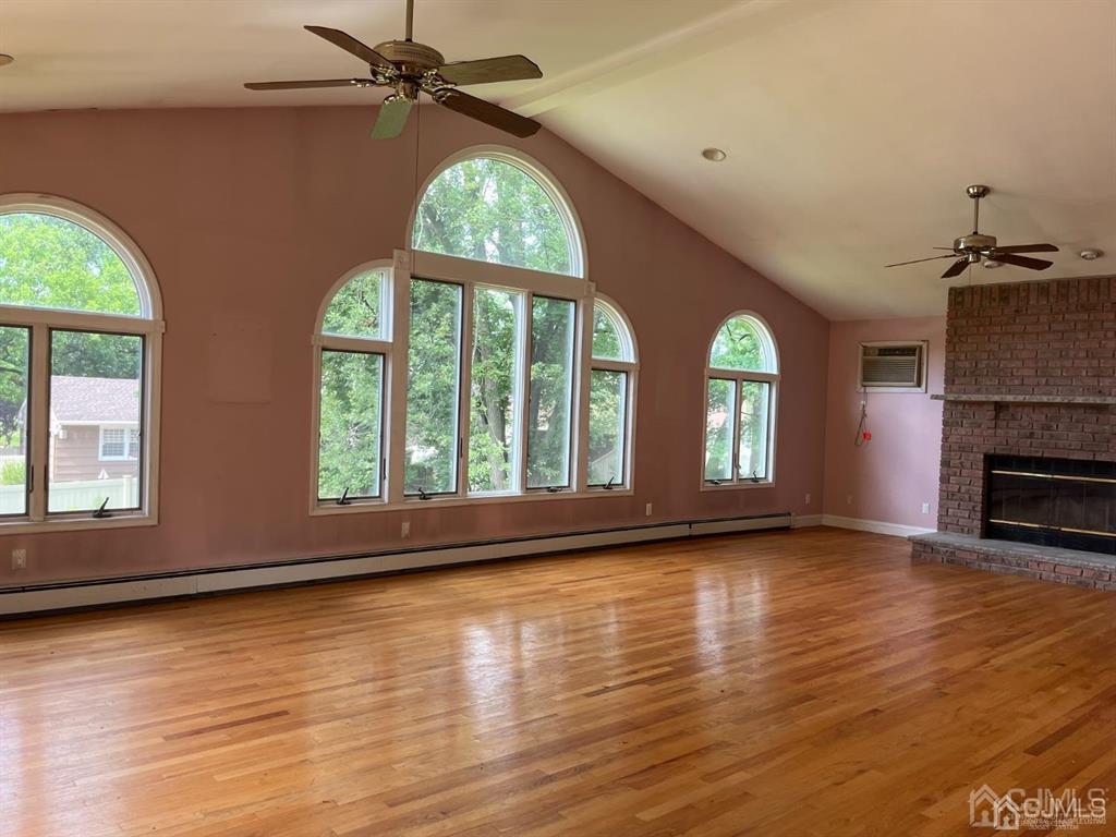 432 Oak Ridge Road Clark, NJ 07066 - Photo 4 of 25 an empty room with wooden floor fireplace and windows