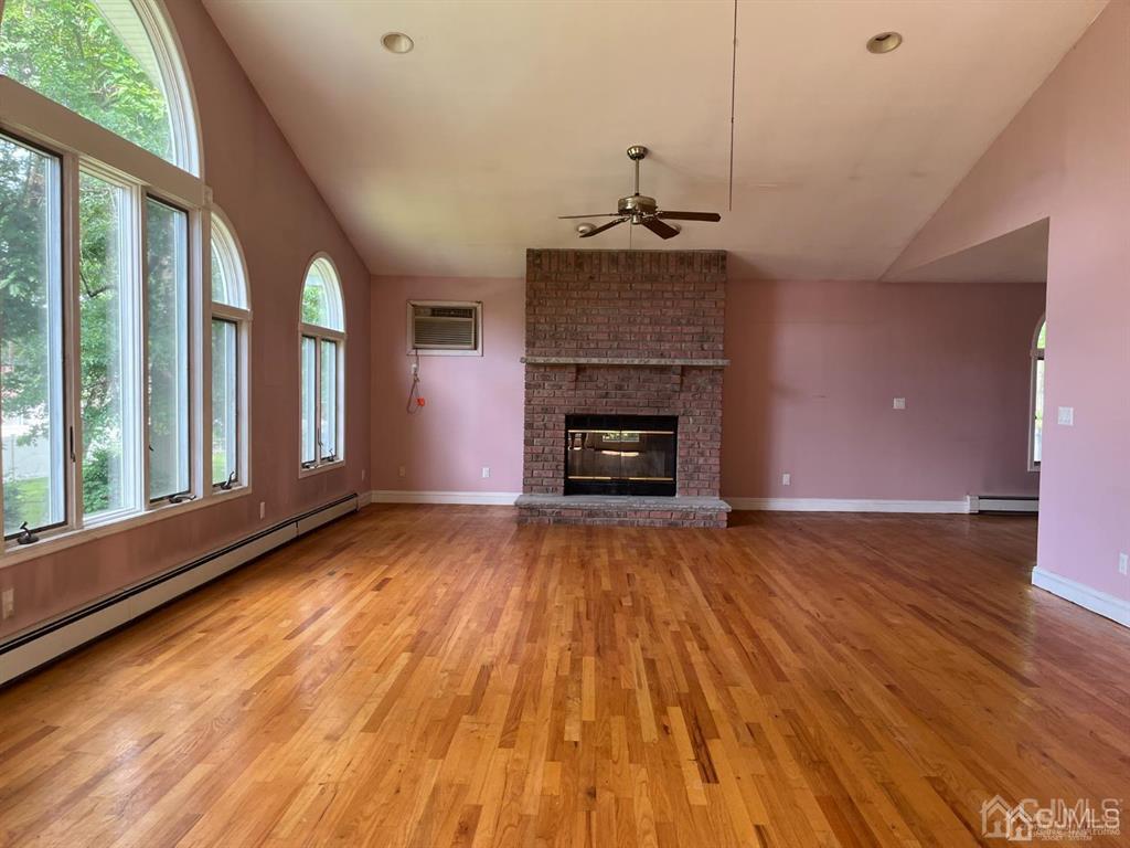 432 Oak Ridge Road Clark, NJ 07066 - Photo 9 of 25 an empty room with wooden floor fireplace and windows