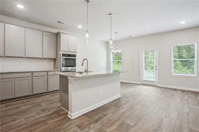 a kitchen with stainless steel appliances granite countertop a sink a stove and a wooden floors