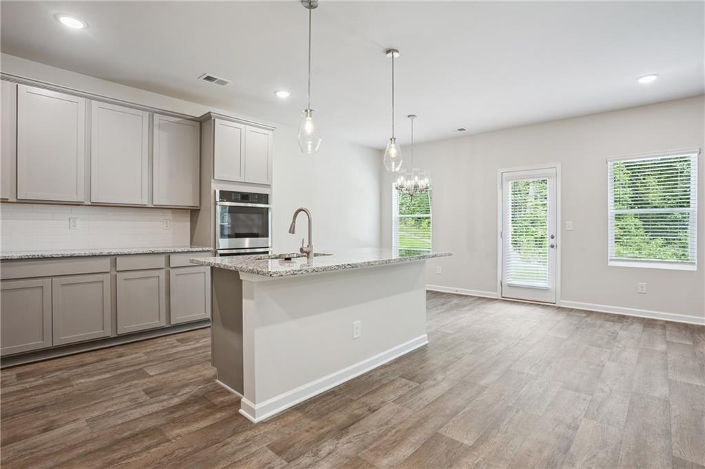685 Egrets Landing, Unit 58 Covington, GA 30014 - Photo 11 of 41 a kitchen with stainless steel appliances granite countertop a sink a stove and a wooden floors