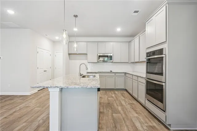 a kitchen with stainless steel appliances granite countertop a sink a stove a refrigerator and white cabinets