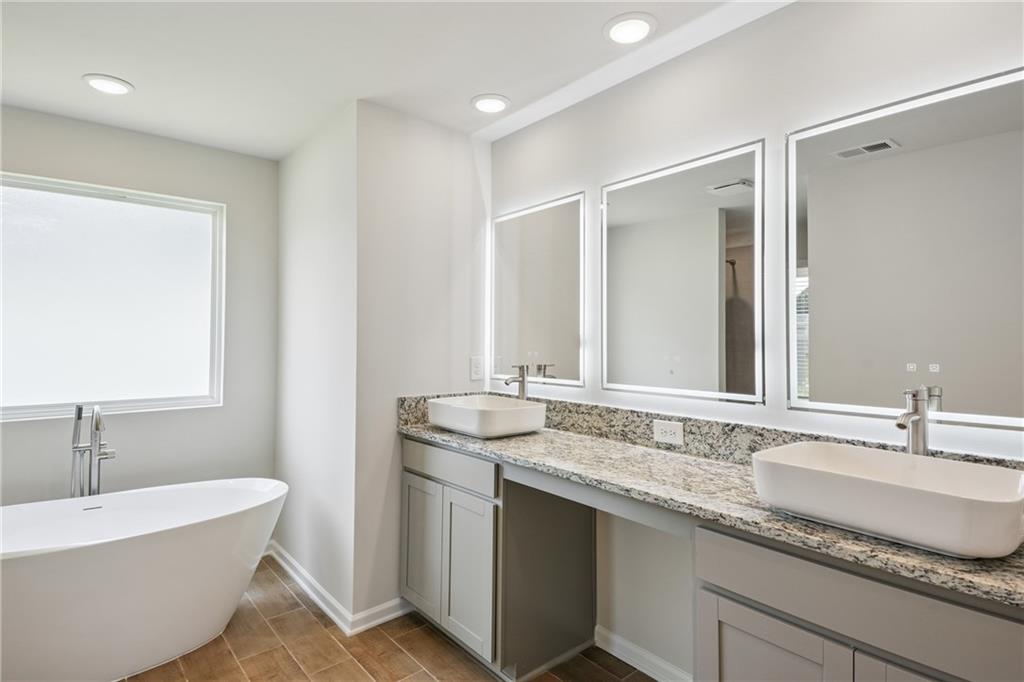 685 Egrets Landing, Unit 58 Covington, GA 30014 - Photo 19 of 41 a bathroom with a granite countertop bathtub sink double and mirror
