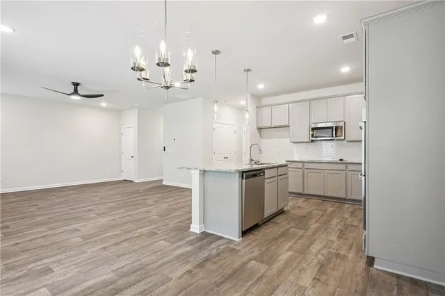 a kitchen with granite countertop a stove a sink and white cabinets with wooden floor