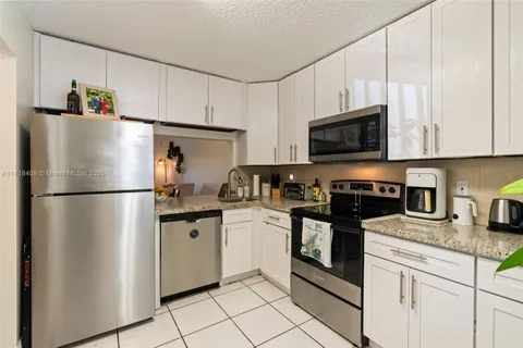 a kitchen with stainless steel appliances granite countertop a refrigerator stove a sink and dishwasher with white cabinets