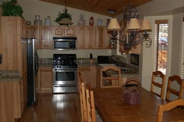 7168 Moon Pinetop, AZ 85935 - Photo 3 of 5 a kitchen with stainless steel appliances granite countertop a refrigerator a stove and a sink with wooden floor