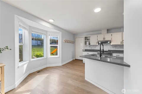 a kitchen with stainless steel appliances granite countertop a sink and a large window