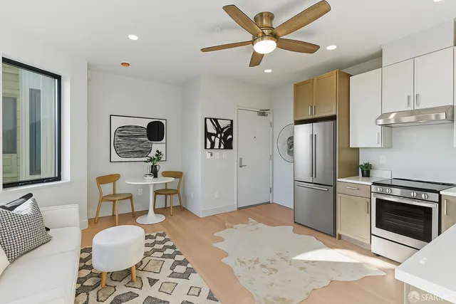 a kitchen with stainless steel appliances granite countertop a refrigerator a sink a stove a dining table and chairs with wooden floor