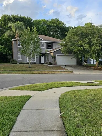 a view of a house with a yard and a large parking space