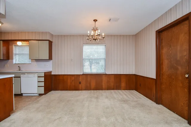 a large white kitchen with a sink and dishwasher a stove top oven with wooden floor