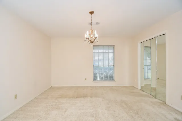a view of an empty room with chandelier fan