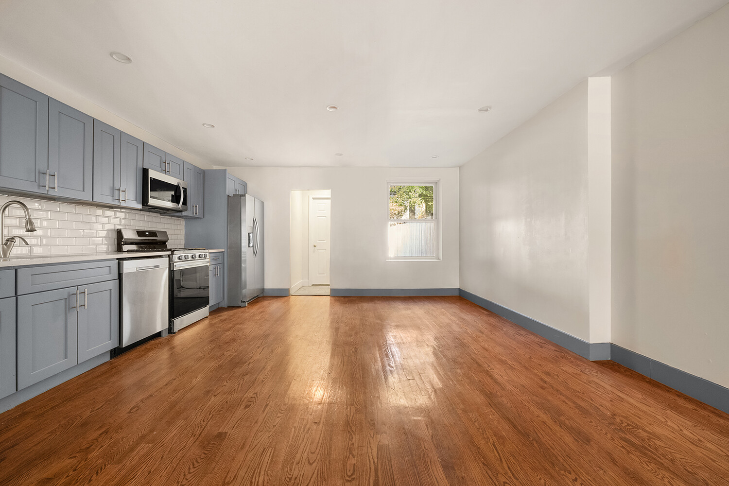 497 Decatur Street Brooklyn, NY 11233 - Photo 6 of 21 a view of a kitchen with wooden floor electronic appliances and window