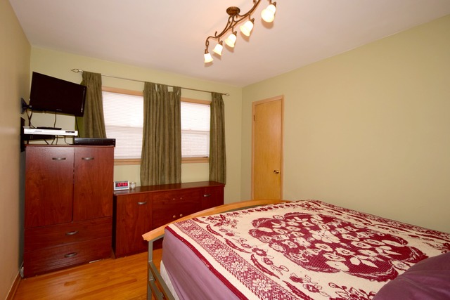 7301 West Roscoe Street Chicago, IL 60634 - Photo 13 of 22 a bedroom with a bed and a flat tv screen on dresser