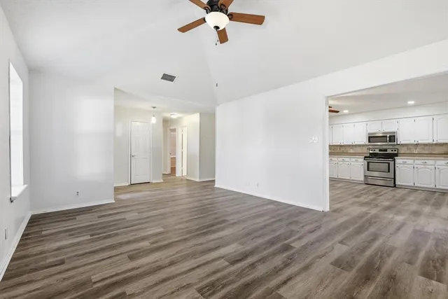 a view of empty room with wooden floor and window