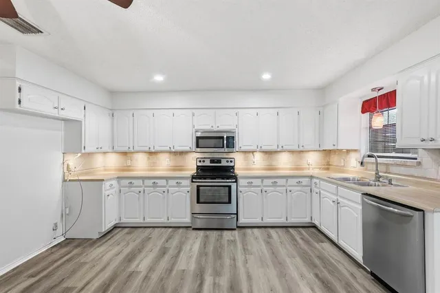a kitchen with granite countertop stainless steel appliances and white cabinets