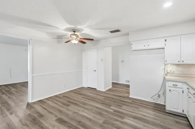 an empty room with wooden floor and ceiling fan