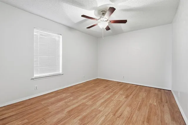 an empty room with a window and a fan