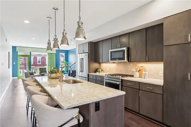 a kitchen with kitchen island granite countertop a sink a counter top space appliances and cabinets