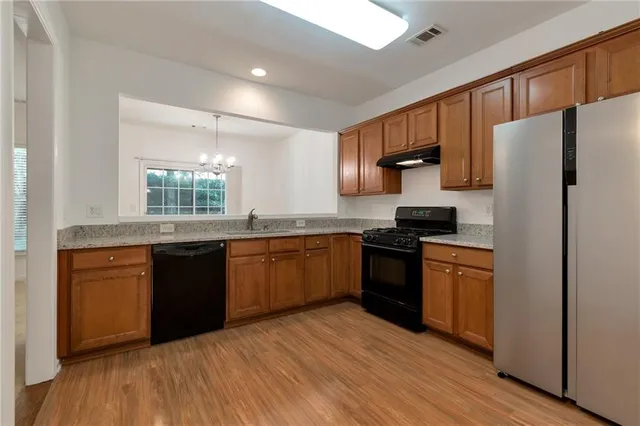 a kitchen with granite countertop a refrigerator stove top oven and sink