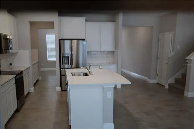 a kitchen with a sink a refrigerator and cabinets
