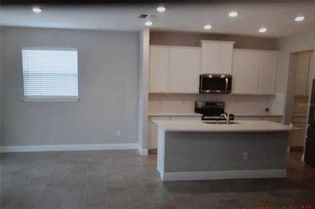 a kitchen with kitchen island stainless steel appliances a sink stove and cabinets