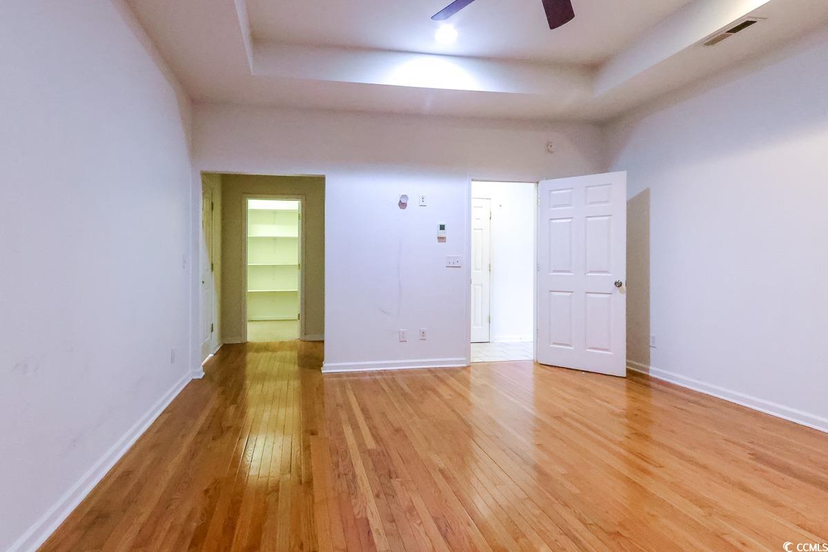 2191 Jasmine Road Loris, SC 29569 - Photo 15 of 40 Empty room featuring light wood finished floors, a tray ceiling, ceiling fan, and baseboards