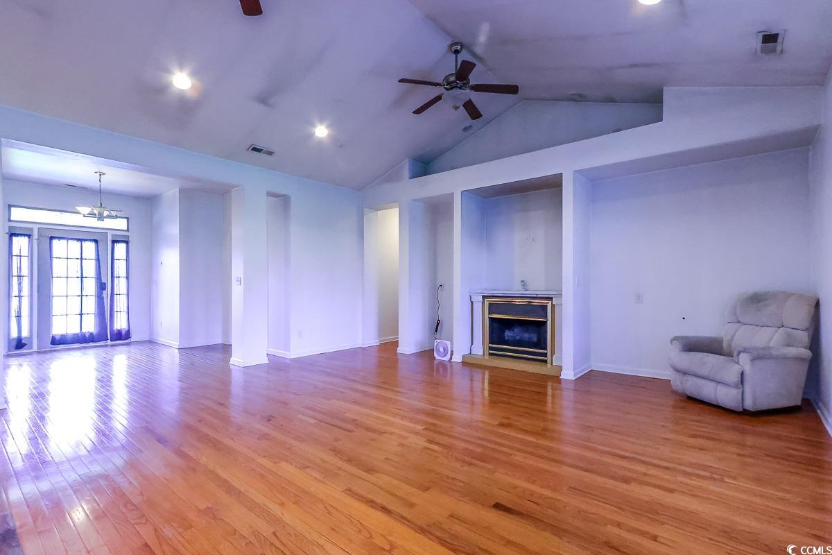 2191 Jasmine Road Loris, SC 29569 - Photo 6 of 40 Unfurnished living room featuring a glass covered fireplace, a chandelier, light wood-style flooring, baseboards, and a ceiling fan