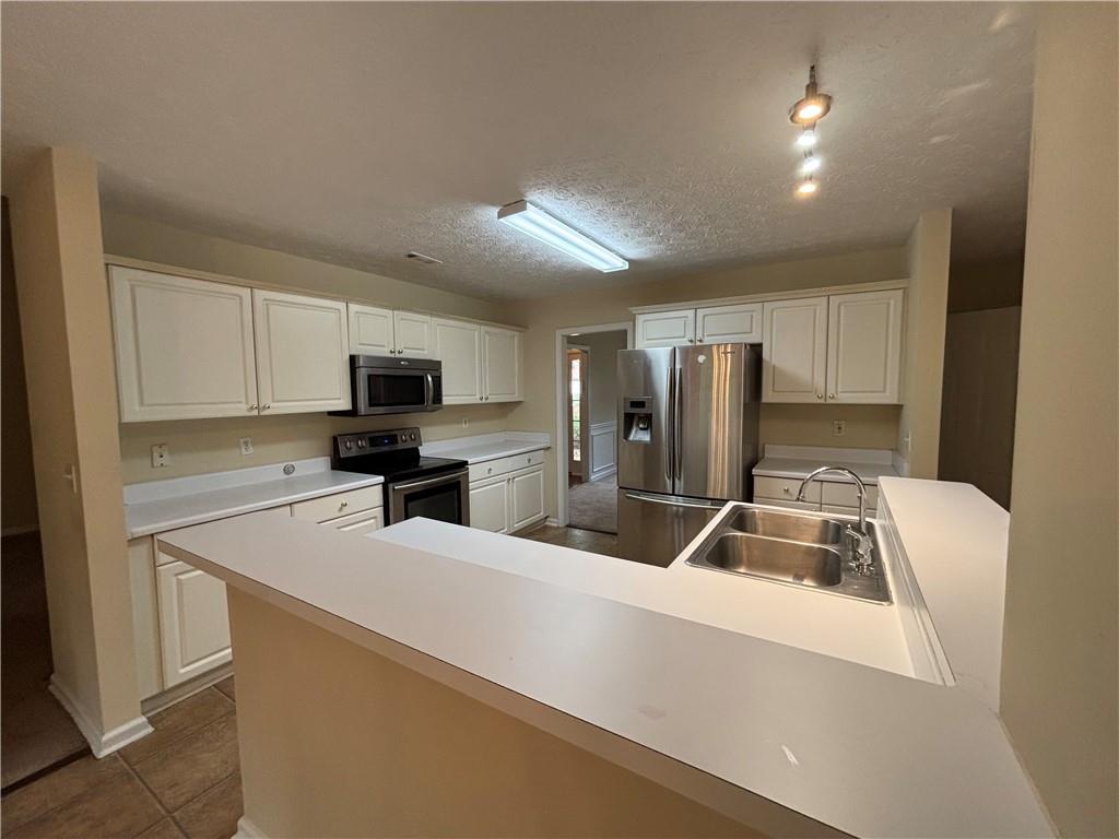 170 Gibson Way Covington, GA 30016 - Photo 32 of 50 a kitchen with a refrigerator a sink a stove a microwave and cabinets