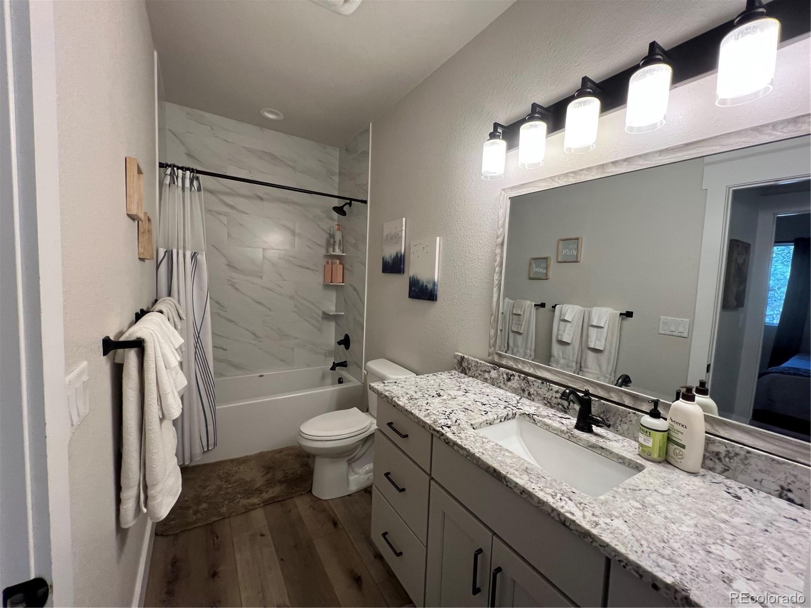 348 Duesouth Road Florissant, CO 80816 - Photo 22 of 28 a bathroom with a granite countertop sink toilet mirror and shower