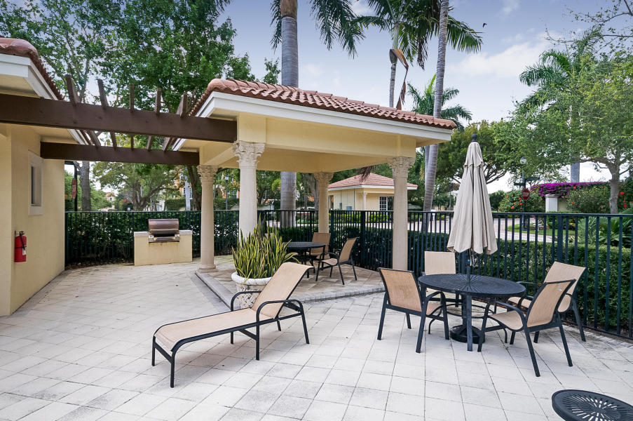 5610 Northeast Trieste Terrace Boca Raton, FL 33487 - Photo 36 of 44 a view of a patio with table and chairs potted plants and a palm tree