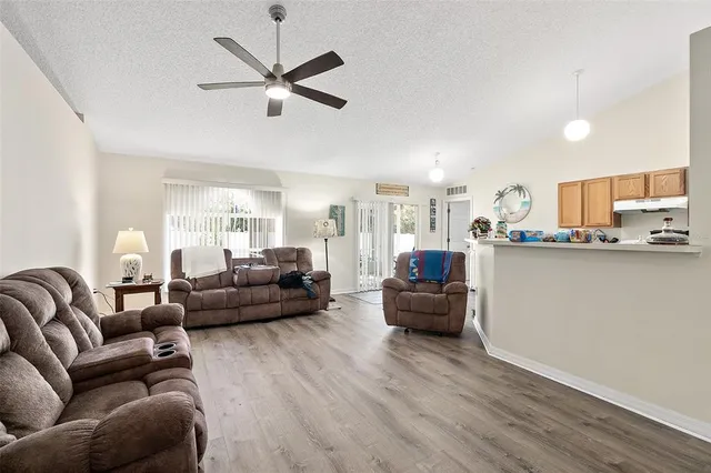 a living room with furniture kitchen view and a wooden floor