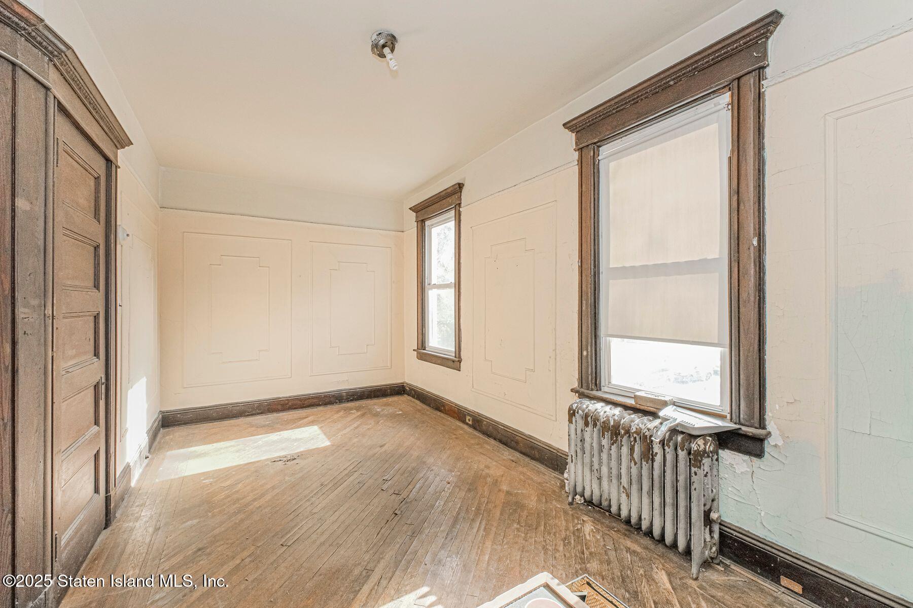316 Sherman Street Brooklyn, NY 11218 - Photo 23 of 26 an empty room with wooden floor and windows