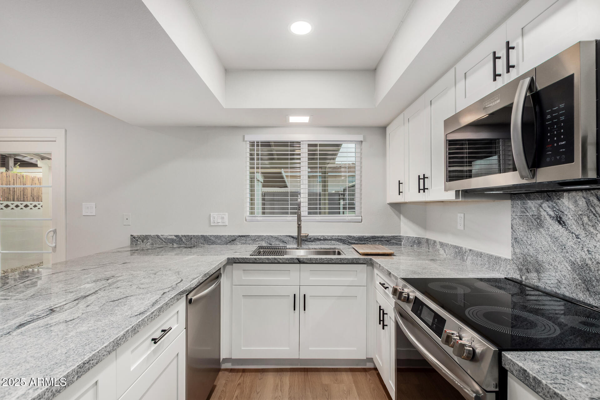 6027 North Granite Reef Road Scottsdale, AZ 85250 - Photo 10 of 29 a kitchen with stainless steel appliances granite countertop a sink stove and microwave