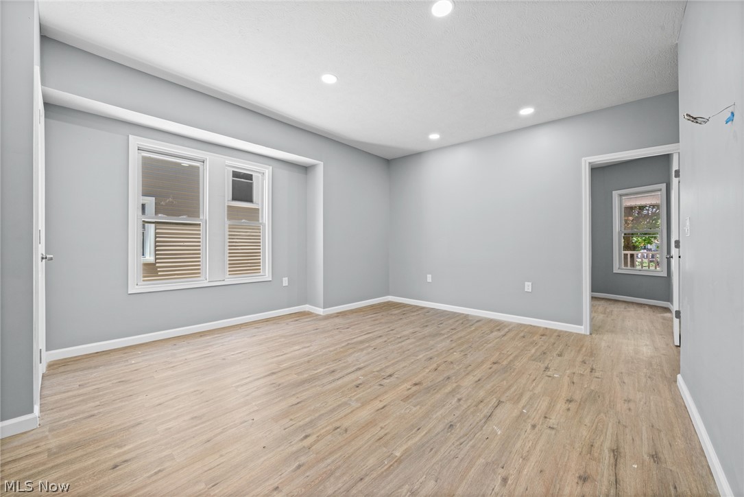 3925 Riverside Avenue Cleveland, OH 44109 - Photo 9 of 48 Spacious room featuring wood-finish flooring, light grey painted walls, white trim, recessed lighting, and a double window with white framing