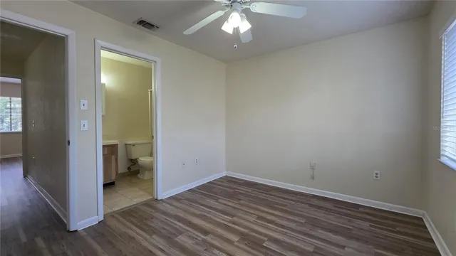 an empty room with wooden floor closet and windows