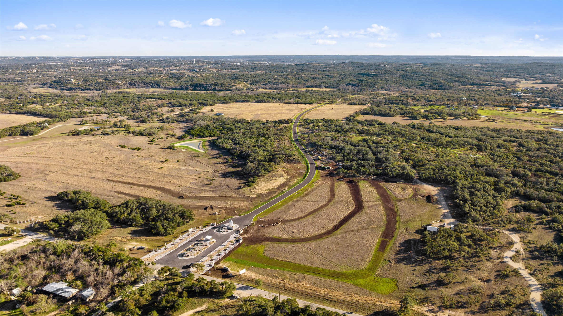 Lot 3 West Fitzhugh Road Dripping Springs, TX 78620 - Photo 7 of 7 An aerial perspective reveals a developing community with a winding road amidst natural terrain and verdant stretches.