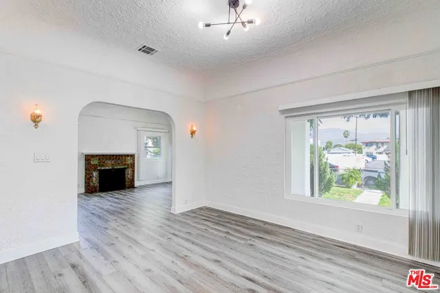 an empty room with windows and fireplace