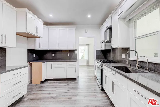 a kitchen with granite countertop white cabinets sink and stainless steel appliances