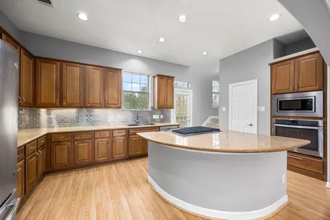 a large kitchen with stainless steel appliances granite countertop a large kitchen counter top a stove and a wooden floors