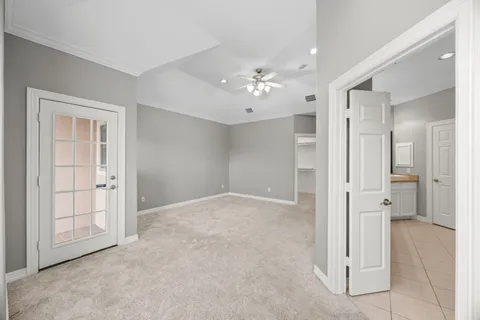 an empty room with a chandelier fan and windows