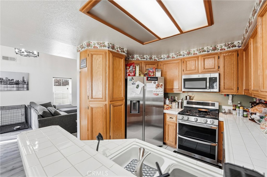 7639 Hillhurst Drive Riverside, CA 92508 - Photo 26 of 60 a kitchen with stainless steel appliances kitchen island granite countertop a refrigerator and a stove top oven