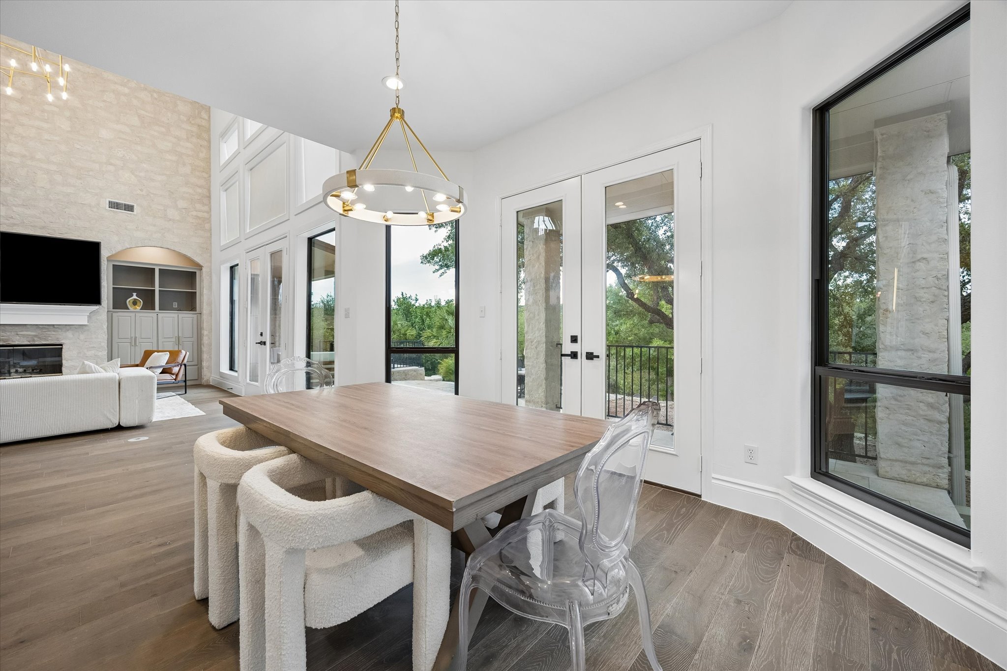 3719 Bee Creek Road Spicewood, TX 78669 - Photo 13 of 40 Natural light floods this dining area, featuring a dramatic chandelier and seamless access to outdoor vistas.