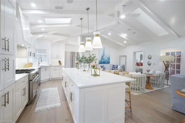 a kitchen with stainless steel appliances kitchen island granite countertop a stove top oven a sink a dining table and chairs with wooden floor